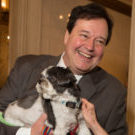 Joe Bowerman smiles while holding his dog, Snoot