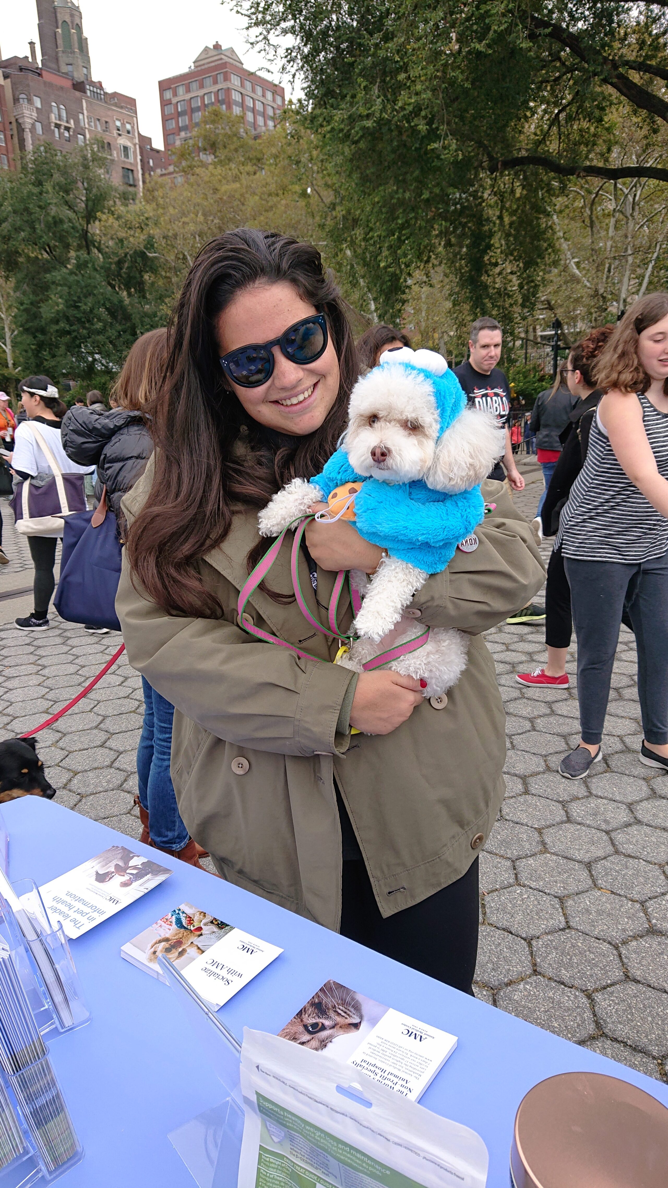 Woman holding a dog wearing a costume