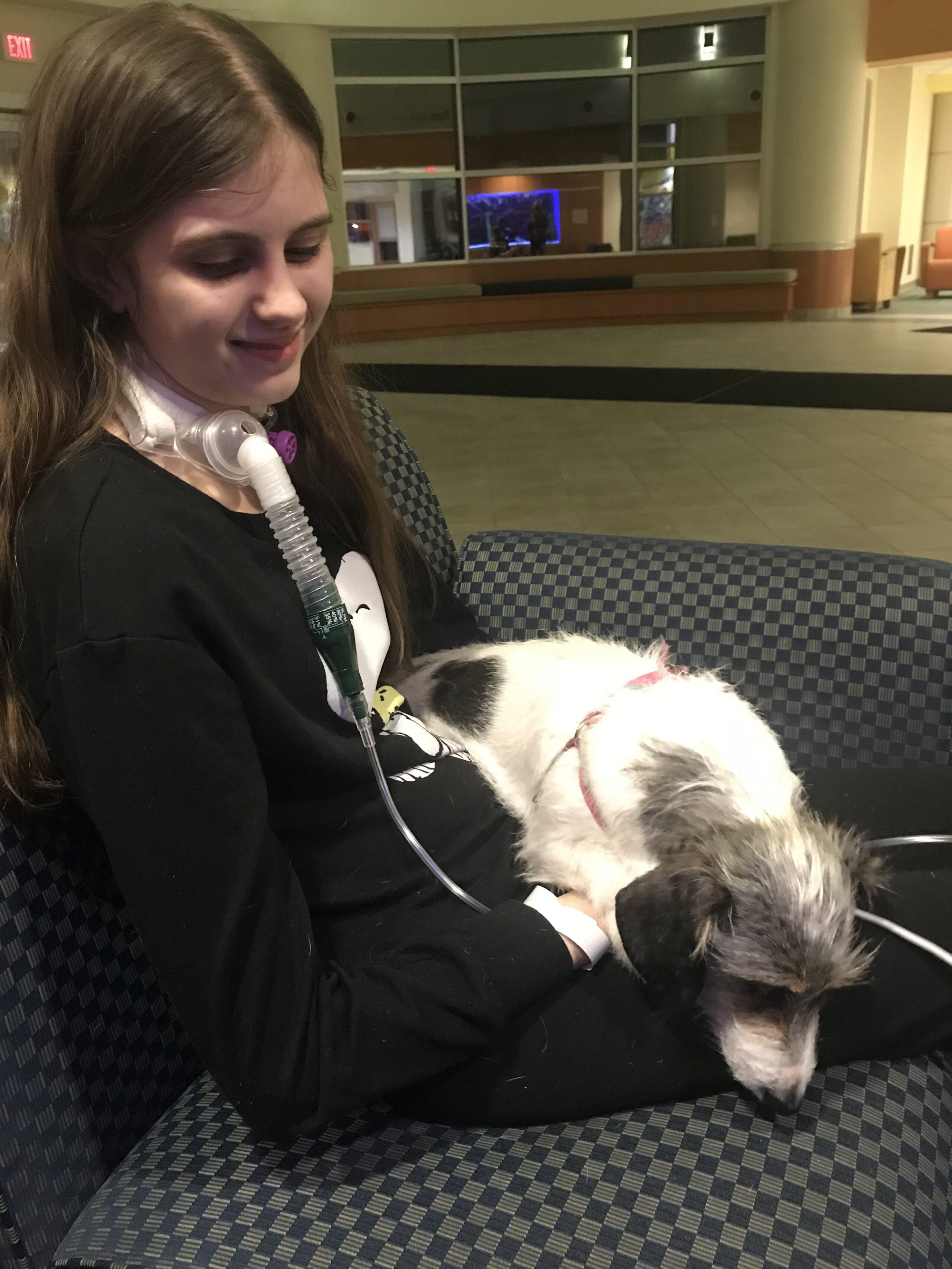 A young woman in a hospital with her dog