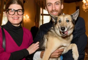 Elsa the dog being held up by her owners for a picture at an AMC living legends event