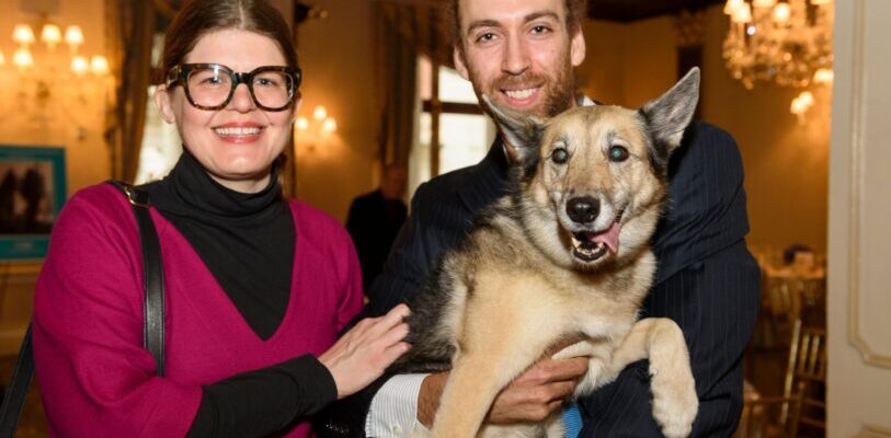 Elsa the dog being held up by her owners for a picture at an AMC living legends event