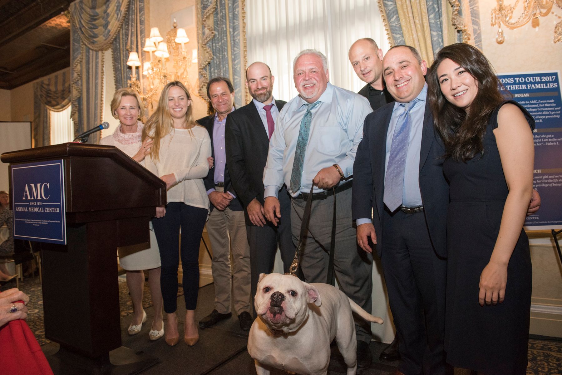 Sugar the dog standing with her owner and AMC staff being honored as a living legend