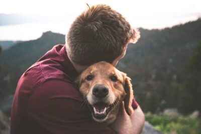 A man hugging a dog in nature