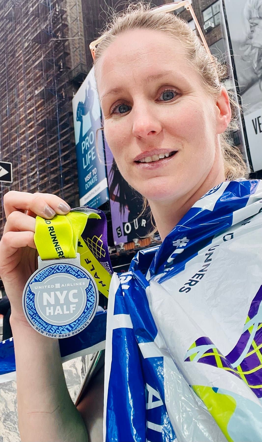A half marathon runner holds up her medal