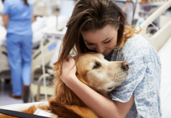 A woman in a hospital with a therapy dog
